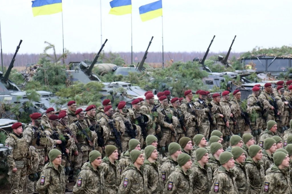 Українська армія у строю з прапорами та військовою технікою на фоні
