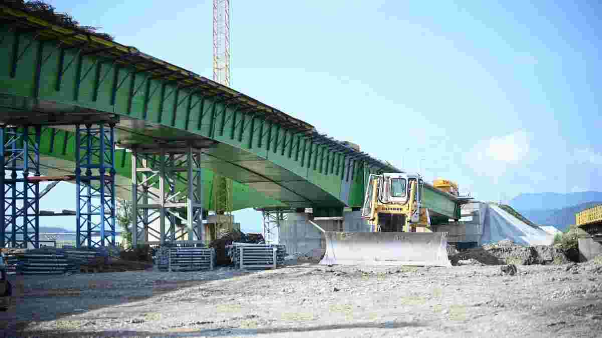Будівництво зеленого сталевого мосту з жовтою технікою на майданчику