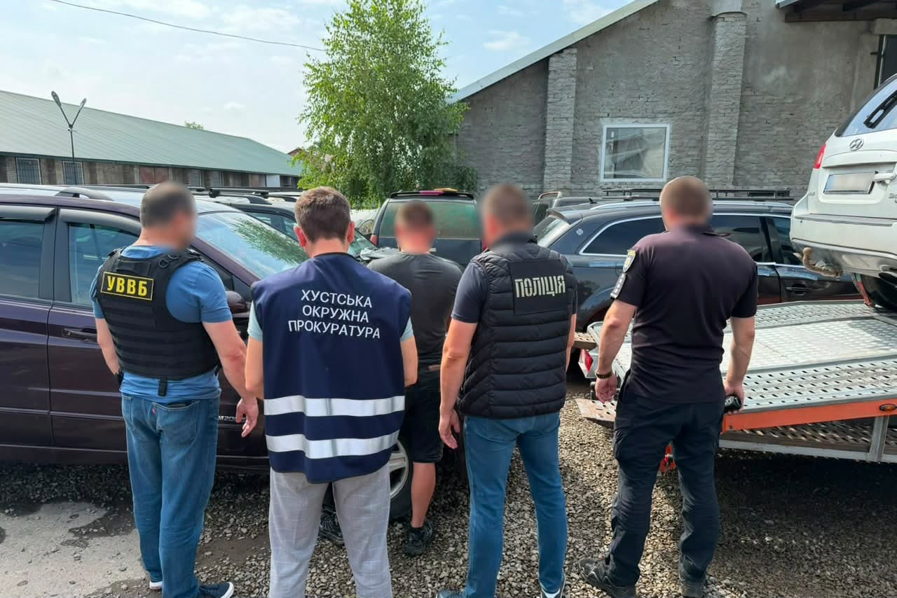 Поліцейські та прокурори оглядають автомобілі на стоянці біля будівель
