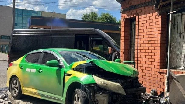 Розбитий зелено-жовтий Kia з пошкодженим передом біля цегляної стіни після ДТП