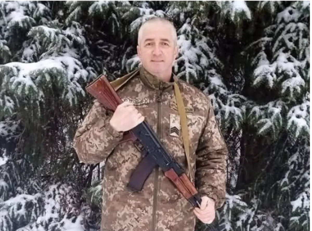 Чоловік у камуфляжі тримає автомат серед засніжених ялин у лісі
