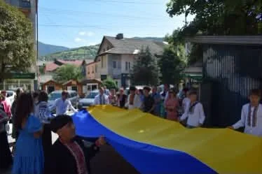 Мешканці Рахова несуть великий державний прапор України вулицею під час ходи пам’яті