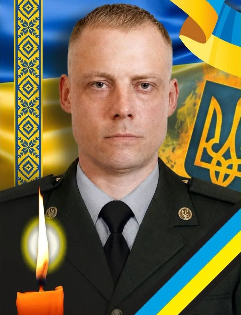 Портрет чоловіка у військовій формі на тлі прапора і герба України з запаленою свічкою