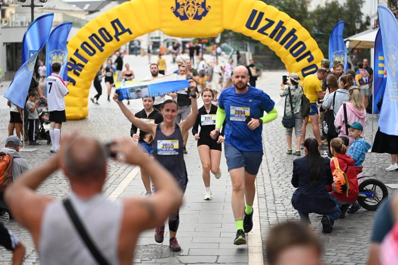 Бігуни пробігають під жовтою аркою Ужгород серед глядачів на площі