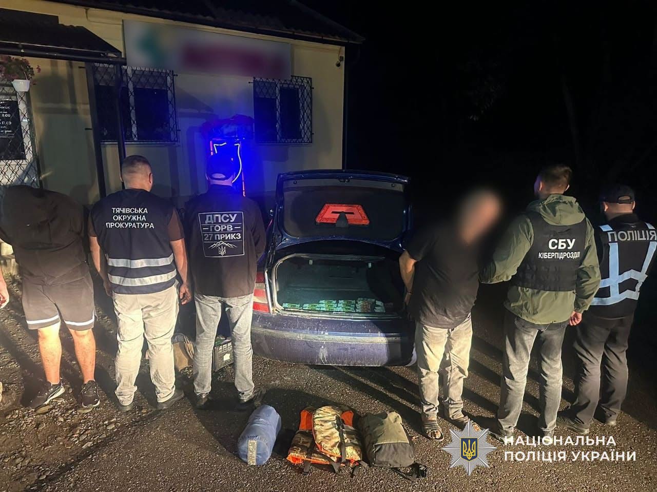 Правоохоронці вночі оглядають відкритий багажник авто та речі на землі