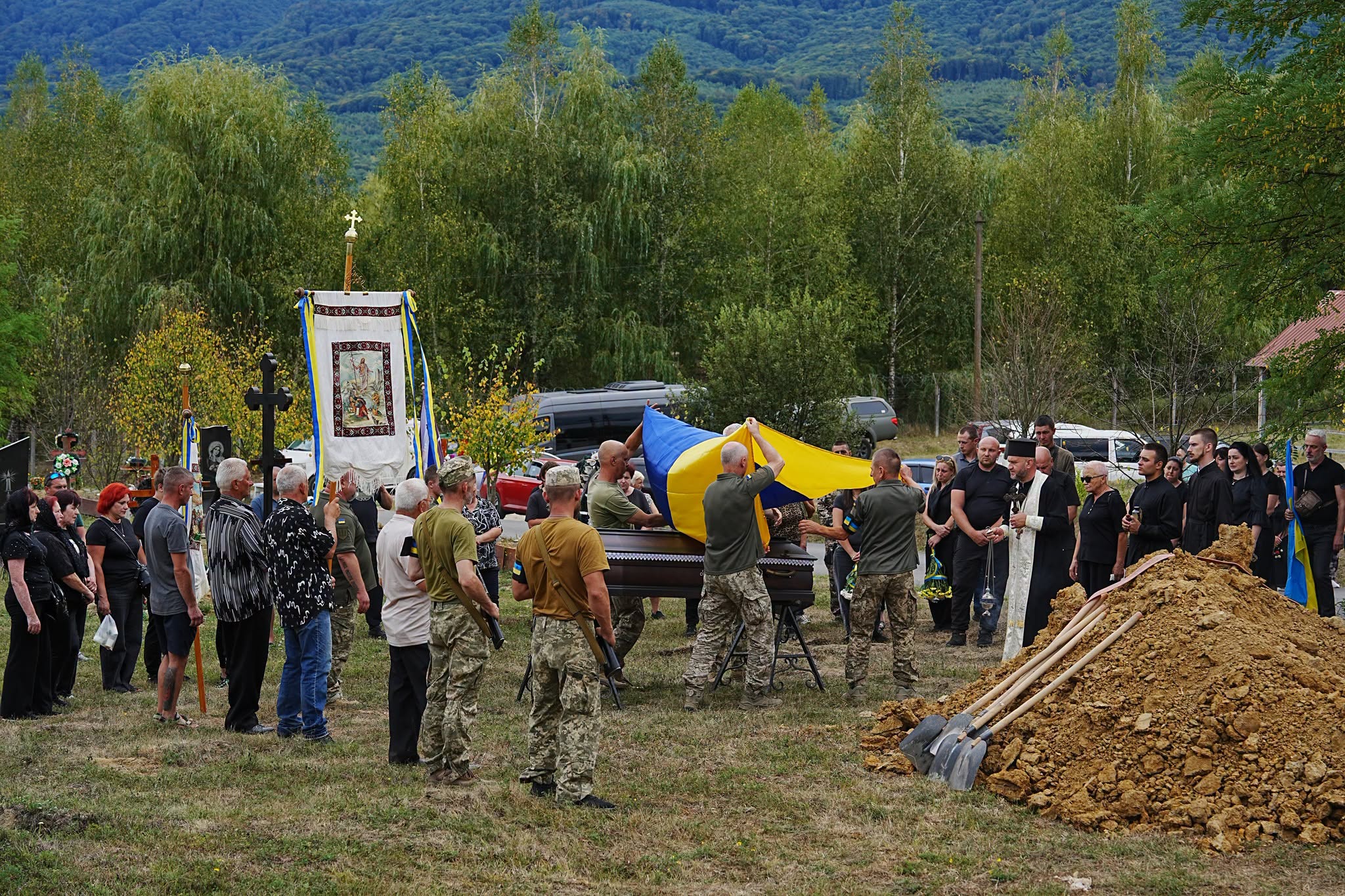 Військові накривають труну прапором України на похороні біля могили в Перечині