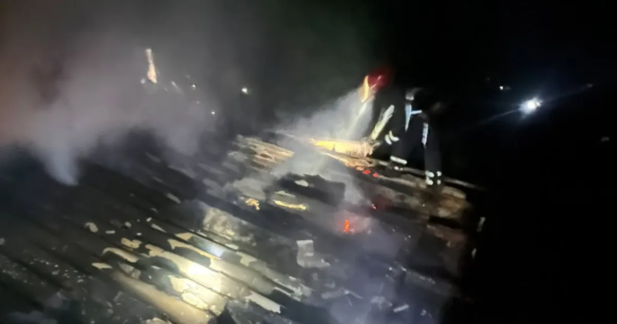Рятувальники гасять пожежу в хліві вночі, видно вогонь та дим